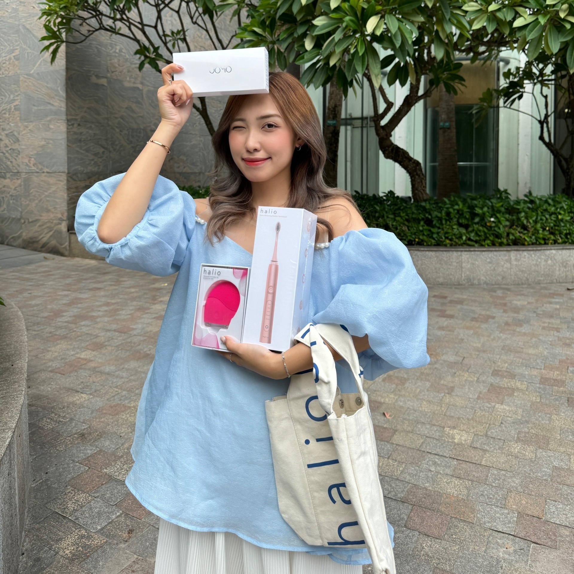 Cô gái trẻ cầm trên tay các sản phẩm GWP đến từ Lixibox, bao gồm bộ làm sạch da và bộ sản phẩm Halio. Hình ảnh này ghi lại sự phấn khích của các TikToker khi tham gia chương trình GWP2010, nơi mà quà tặng trị giá lên đến 3 triệu đồng đang thu hút sự chú ý của nhiều người yêu làm đẹp.