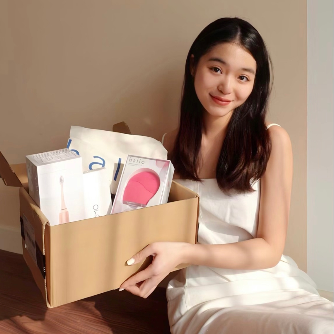 Cô gái đang cười tươi, cầm một hộp quà GWP 2010 của Lixibox, cho thấy sự phấn khởi khi nhận được quà trị giá lên đến 3 triệu đồng từ chương trình GWP đang thu hút đông đảo sự quan tâm của TikToker và beauty blogger.