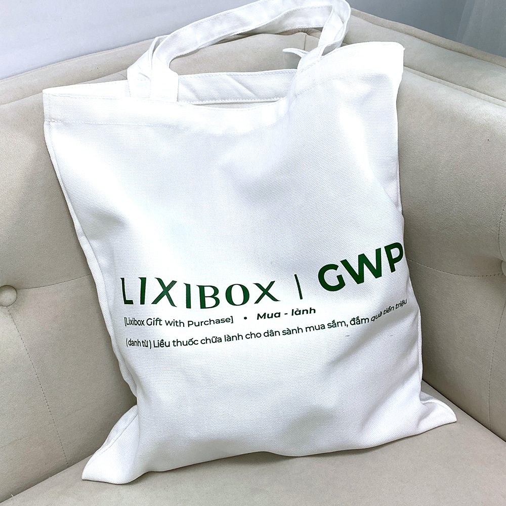 Túi vải màu trắng với chữ in "LIXIBOX | GWP (Luxibox Gift with Purchase) Mua lành". Túi mang thông điệp về chương trình GWP của Lixibox, liên quan đến việc chữa lành bản thân hậu tan vỡ và các dịp khuyến mãi hấp dẫn.