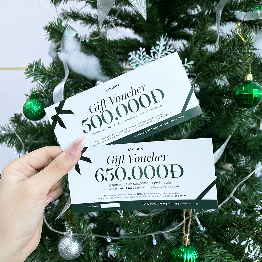 Hai phiếu quà tặng Lixibox với giá trị 500.000₫ và 650.000₫, nằm giữa cây thông Noel. Hình ảnh khuyến mãi hấp dẫn cho dịp mua hàng cuối năm, liên quan đến GWP và review hộp quà chữa lành sau sự cố tình cảm.