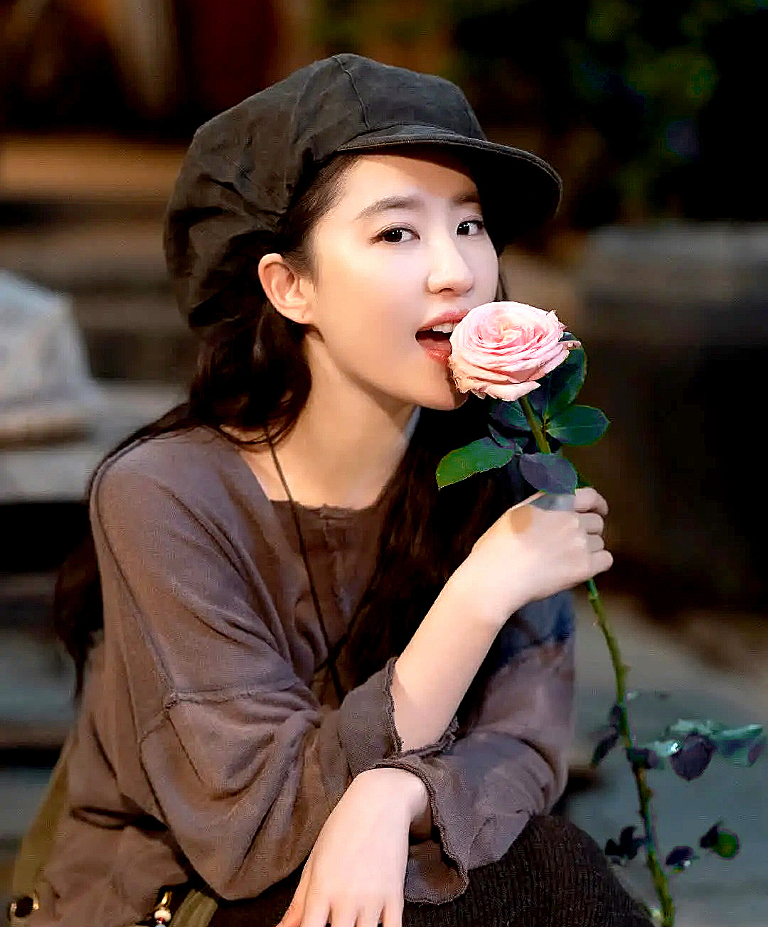 Cô gái trẻ đang tạo dáng với hoa hồng, mặc áo phông rộng rãi và đội mũ lưỡi trai. Bức ảnh thể hiện vẻ đẹp tự nhiên và phong cách thoải mái, phù hợp với các xu hướng thời trang hiện đại. Bài viết "Thánh tạo trend" 2023 đưa ra danh sách 7 nữ ngôi sao nổi bật.
