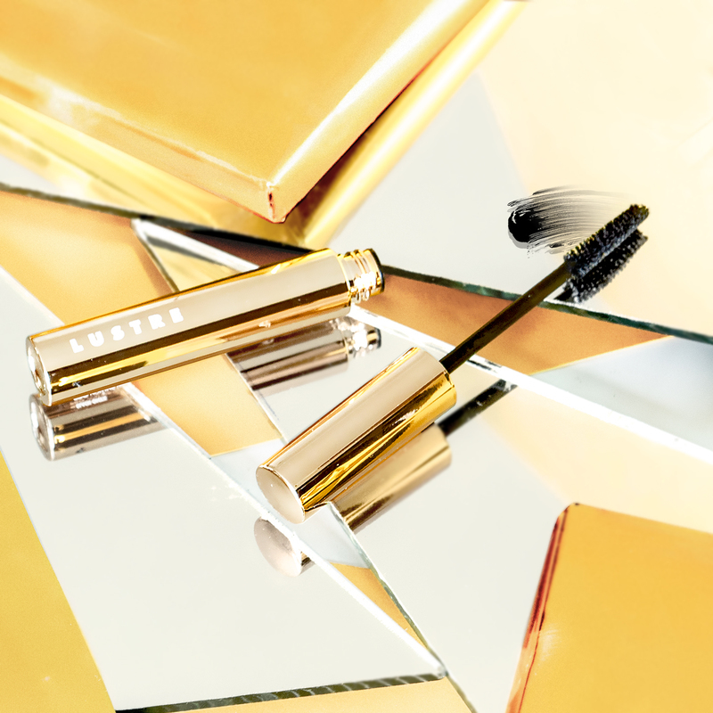 Lọ mascara Lustre cùng với chổi mascara chống nước trên nền gương phản chiếu, bài viết giới thiệu 6 loại mascara tốt nhất dành cho các bạn gái trong mùa mưa Sài Gòn, giúp giữ cho làn mi luôn đẹp và bền lâu.