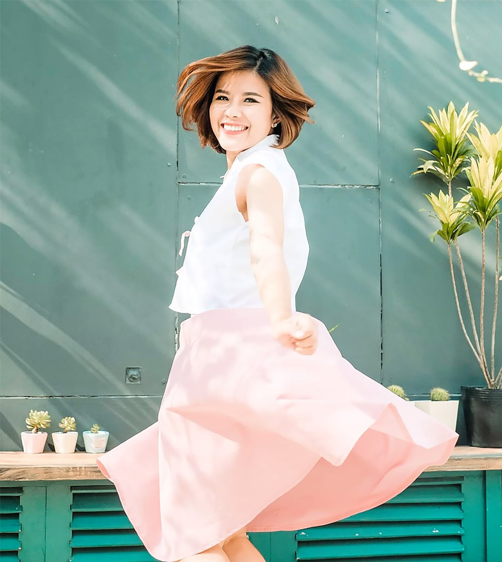 CEO Lynh Thuỳ đang vui vẻ diện váy hồng, tạo dáng sáng tạo bên những chậu cây nhỏ. Bài viết "Trong đám cưới, mọi thứ có thể qua loa nhưng cô dâu nhất định phải đẹp" khám phá sự chú ý đến cái đẹp và phong cách sống tự tin.