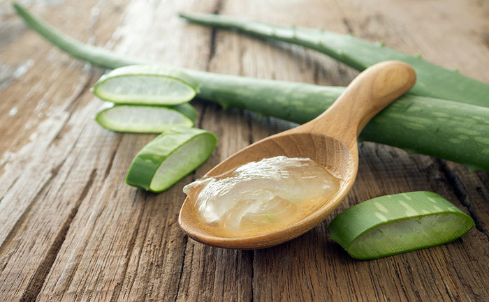 Nha đam tươi và gel nha đam trên muỗng gỗ, biểu tượng cho giải pháp trị thâm và sẹo mụn hiệu quả nhờ vào các phương pháp tự nhiên, giúp dưỡng trắng và ngăn ngừa melanin.