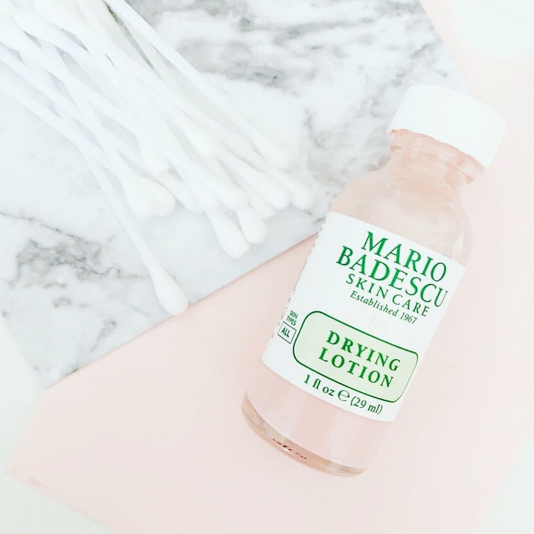 Sản phẩm Mario Badescu Drying Lotion trên nền đá cẩm thạch với bông tăm, là bí quyết chăm sóc da cơ bản giúp dẹp mụn hiệu quả, mang lại làn da tự tin cho mọi cô nàng.
