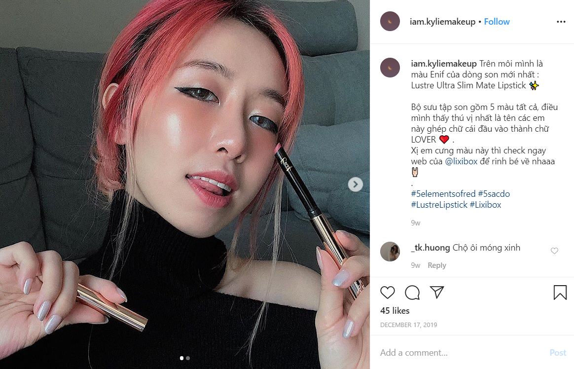 Cô gái trẻ trung với màu tóc hồng, đang cầm thỏi son Lustre Ultra Slim Mate Lipstick, tạo dáng nổi bật. Thiết kế son có hình dáng điếu thuốc độc đáo, sử dụng màu sắc thời thượng, thông tin về mẫu son thu hút được nhiều sự quan tâm trên mạng xã hội của tín đồ làm đẹp từ Lixibox.