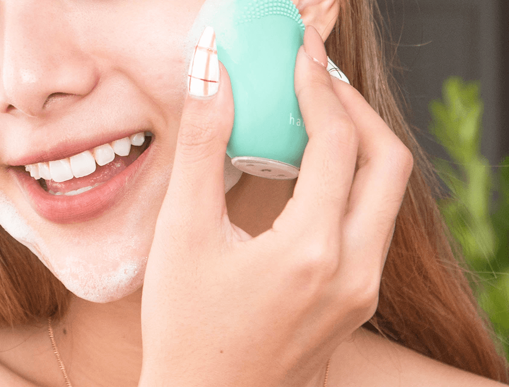 Cô gái trẻ đang sử dụng máy rửa mặt Halio để làm sạch da mặt. Bài viết khám phá lợi ích của việc kết hợp máy rửa mặt và máy đẩy tinh chất dưỡng trắng, giúp nâng cao hiệu quả skincare cho các cô nàng yêu thích làm đẹp.