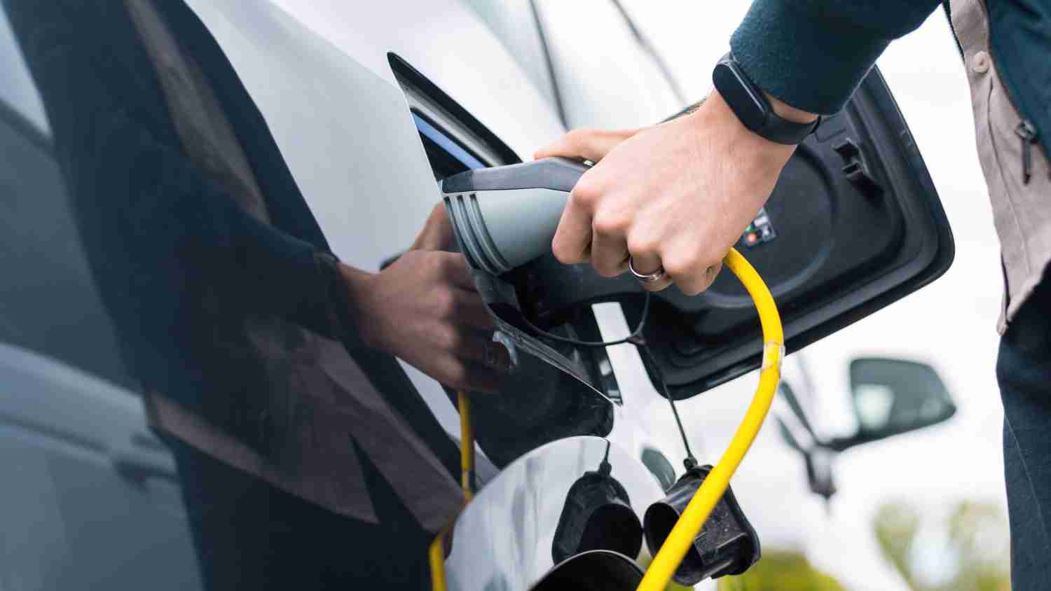 Editors%2 Fimages%2 F1704253658305 Man Plugging Charger Into Electric Car Charge Station+%281%29