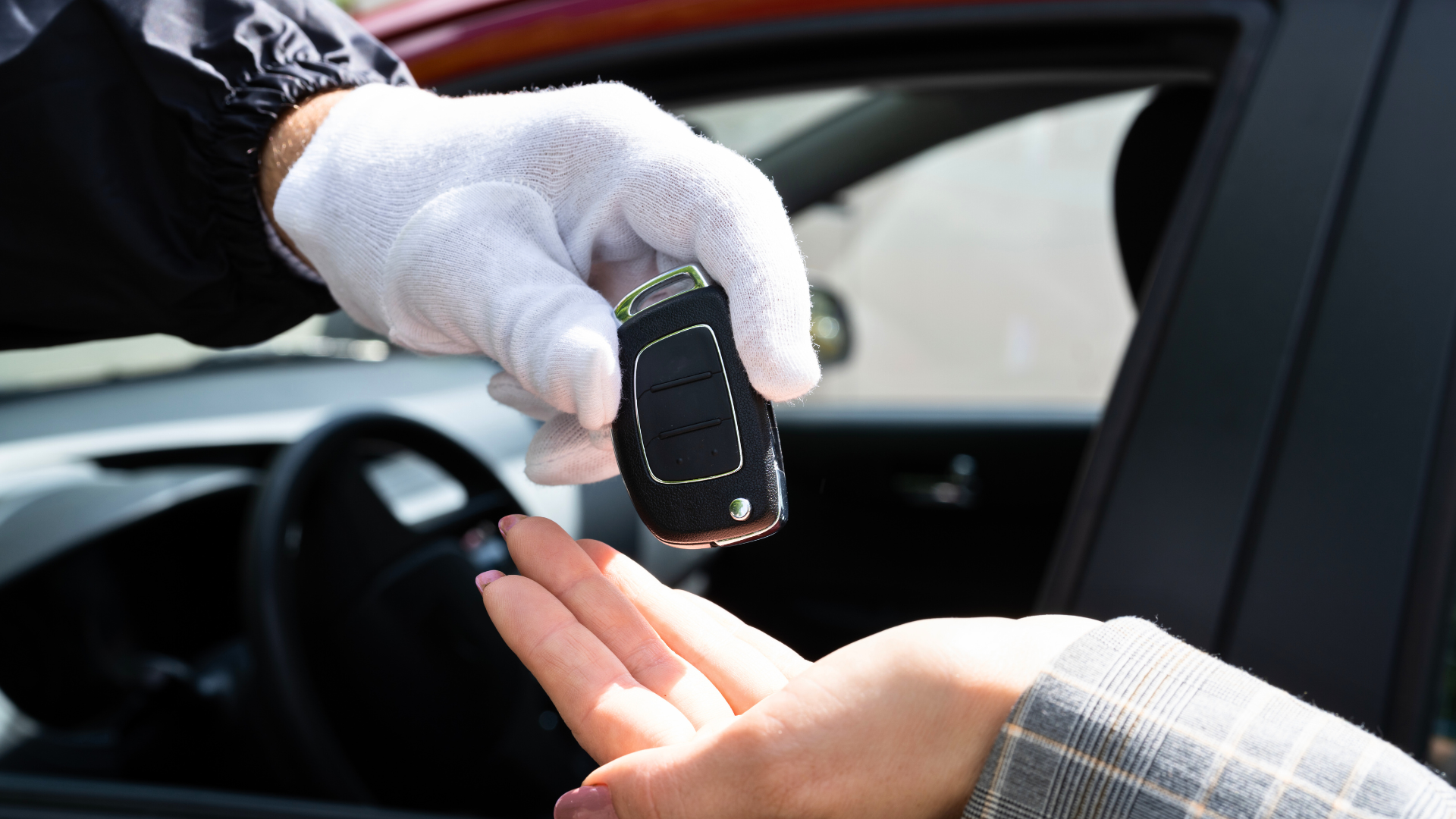 A valet attendant standing next to a luxury car, ready to assist a customer in a bustling hotel parking area.