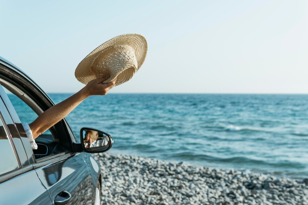 Editors%2 Fimages%2 F1739849672137 Mid Shot Woman Hand Out Car Window Holding Hat Near Sea 23 2148756489