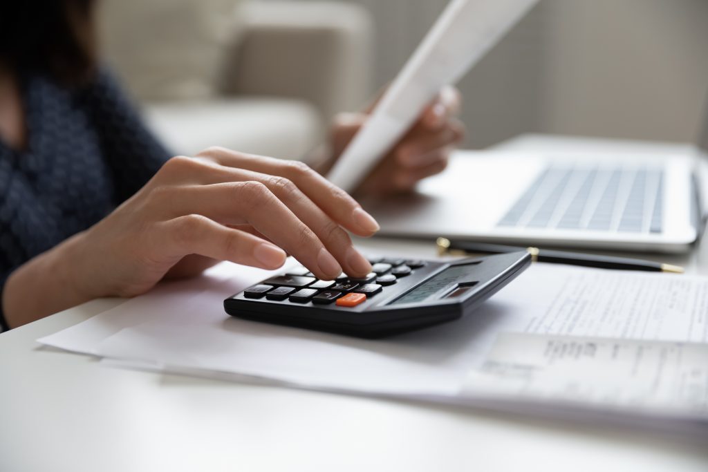 Close up young mixed race woman calculating domestic expenses involved in financial paperwork indoors