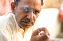 A man smoking in the slums of India.
