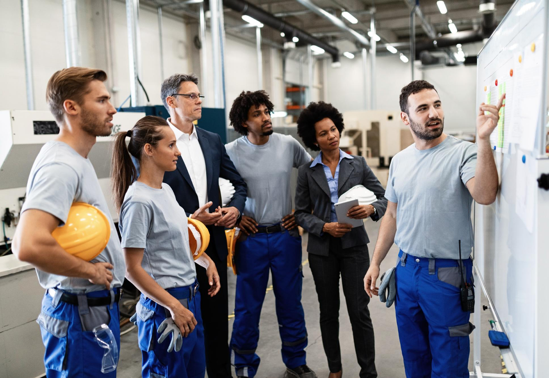 Mixed group of workers and supervisors reviewing tasks on a whiteboard