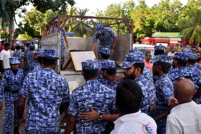 ޖުލައި 29، 2016: އިދިކޮޅު އިއްތިހާދުން އެމްޑީޕީ ހަރުގެ ކުރިމަތީ ބޭއްވި ސައިފޮދަށް ފުލުހުން ހުރަސް އެޅުން: ފުލުހުން ވަނީ އެކަމުގައި ބޭނުން ކުރަމުން ދިޔަ މޭޒުތައް ގެންގޮސްފައި--- ސަން ފޮޓޯ/ މުހައްމަދު އަފްރާހް