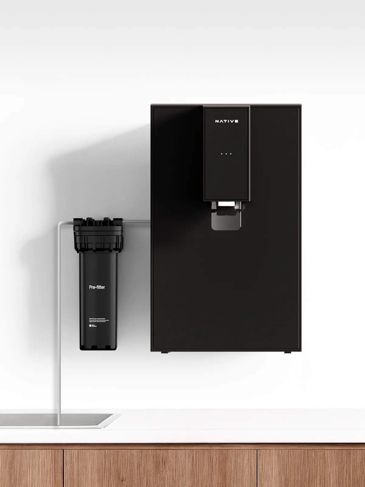 Wall-mounted Native M0 beside a pre-filter joined by a thin inlet pipe.