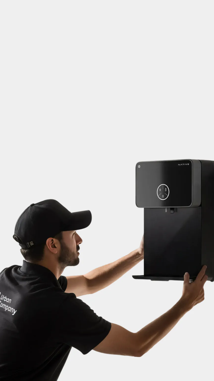 An Urban Company technician installing a Native M1 Pro on a kitchen wall.