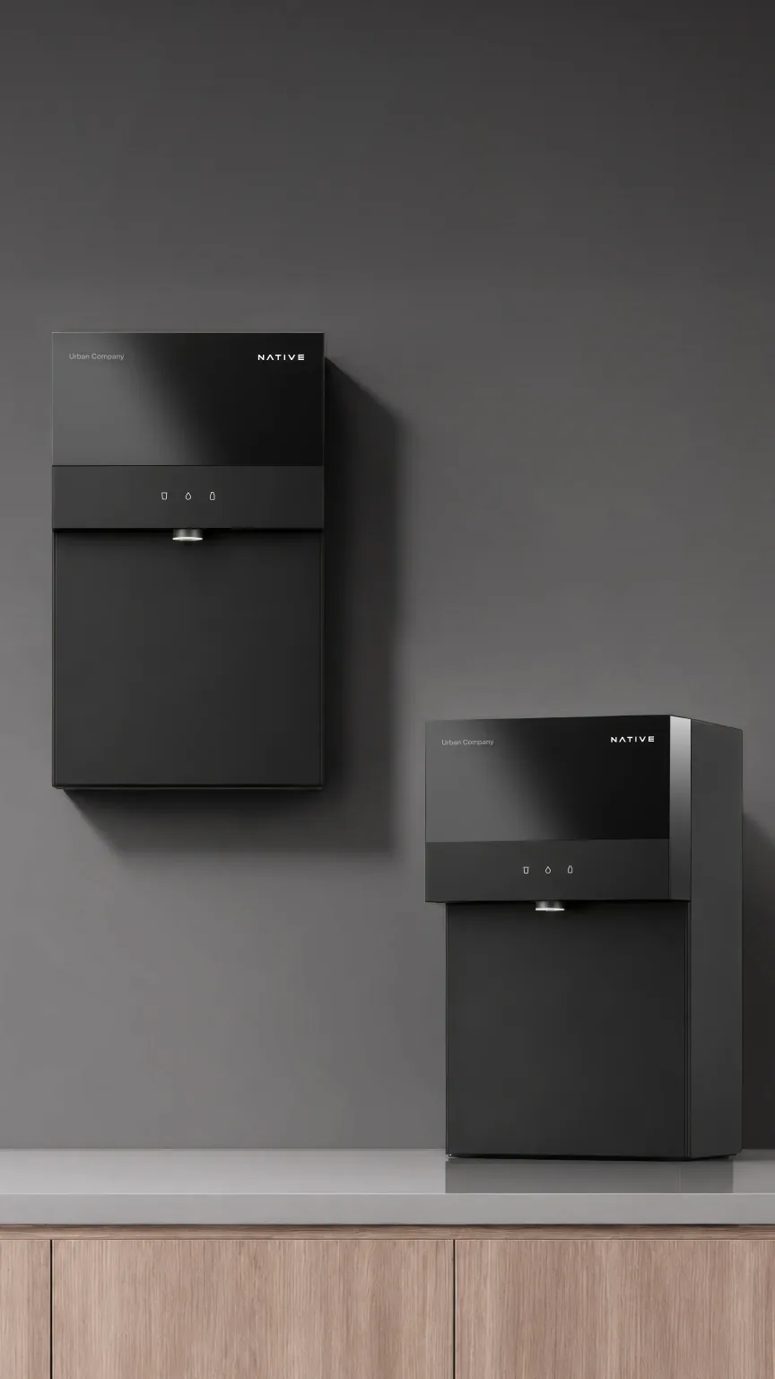 Two Native M3 Pro purifiers against a grey wall, one mounted on the wall and one standing on the counter.